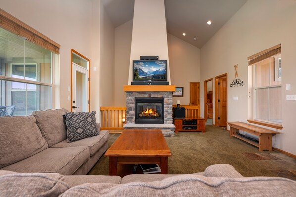 Living area with a large sectional sofa,  flat screen TV and gas fireplace. There are plenty of windows to enjoy the amazing views!