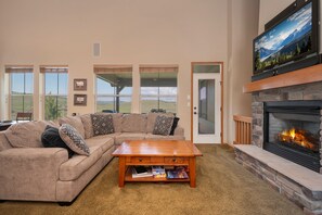 Living area with a large sectional sofa,  flat screen TV and gas fireplace. There are plenty of windows to enjoy the amazing views!