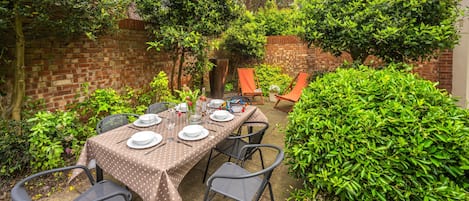 Pretty shrubs and trees surround the garden table and chairs