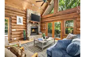 The main living area is open with natural logs and accent lighting throughout.