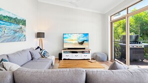 The living room opens to a balcony with the beautiful sight of lush green foliage surrounding the property.