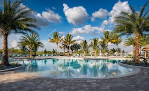 Swim up pool, sandy beach with hammocks behind.