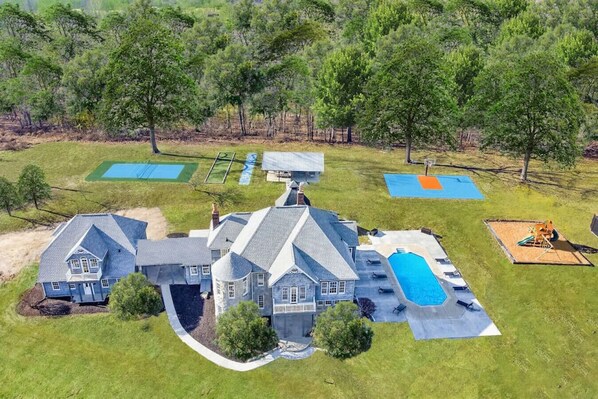 [Resort Property] Aerial View of property with heated pool, pickleball court, basketball, shuffleboard, bocce, playground and more!