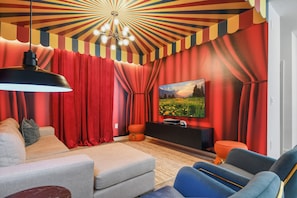 Circus-themed media room with bold colors, cozy seating, and big screen fun.