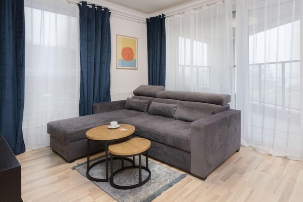 A cozy and modern living room with a gray sofa, wooden accents, and a coffee table, creating a comfortable ambiance.