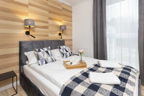 A stylish bedroom featuring a bed with plaid bedding, soft lighting, and wooden panel decor.