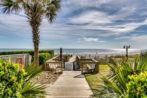 Scenic path through greenery leading to a sparkling, serene beach