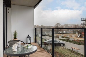 A balcony with outdoor chairs and a small table, offering a peaceful spot to enjoy the surrounding greenery.