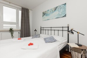 A spacious bedroom featuring a double bed with stylish bedding and a modern lamp on the nightstand.