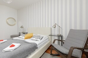 Another bedroom with a cozy bed, minimalist decor, and striped wallpaper for a chic look.