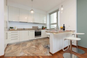 An open-plan kitchen and dining area with a sleek white table and modern chairs, perfect for meals.
