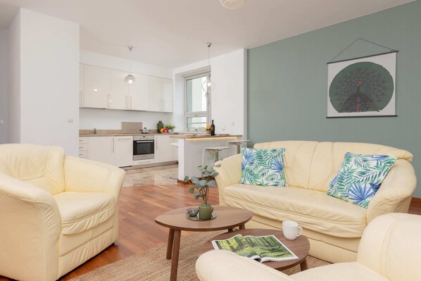 A bright and welcoming living area with a soft beige sofa, a glass coffee table, and decorative artwork.