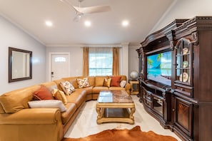Entry area with Samsung TV in solid wood hutch, and luxurious leather sectional 