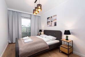 A second bedroom with a double bed adorned with green accents, minimalist furniture, and a relaxing ambiance.