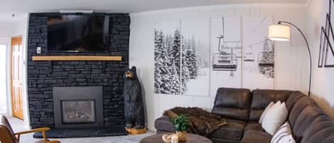 Cozy large sectional with pull out queen size sleeper. Mid century arm chairs around coffee table. Warm gas fireplace with real wood mantle. 55 inch smart Roku TV. Many streaming service options. Beautiful mountain art on the walls.