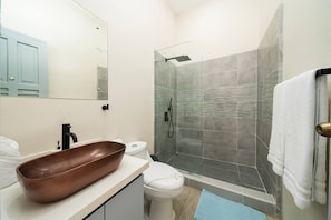 Master bathroom with tiled walk in rain shower and dark copper sink