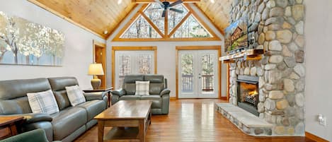 The livingroom features vaulted ceilings and a large stone fireplace