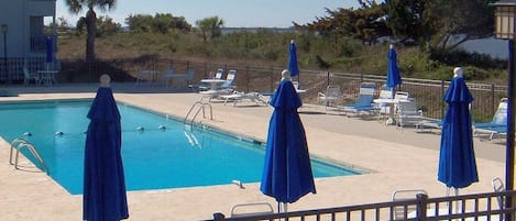 Pool area with plenty of chairs, tables and umbrellas