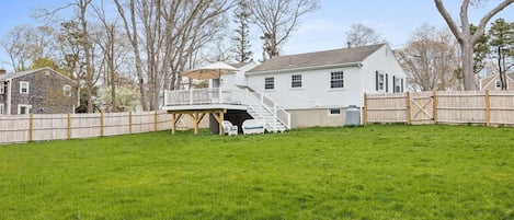 Dog friendly. Another view of the large fenced-in yard and deck with outdoor furniture and outdoor umbrellas