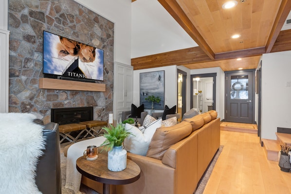 Living Room with leather sectional/sofa sleeper, arm chairs, gas fireplace, and 75" Smart TV
