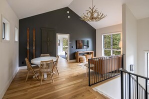 The upper lounge area with cafe work table, smart TV and comfy seating in a light-filled space.