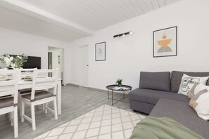 A cozy living room with a gray sofa, complemented by a dining area with a white table and chairs.