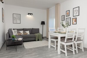 A cozy living room with a gray sofa, complemented by a dining area with a white table and chairs.