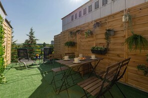 A private outdoor space with a green lawn, wooden fencing, and a seating area with chairs and a table, perfect for relaxing or dining.