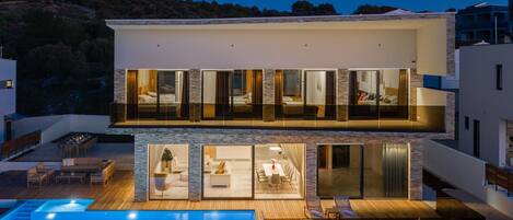 Nachtansicht der Luxusvilla Rogoznica zur Miete mit beheiztem Infinity-Pool und Esstisch im Freien mit Concierge-Service