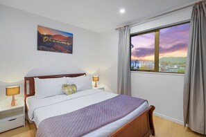 On either side of the bed are matching wood nightstands, each topped with lamps that cast a warm, inviting glow.