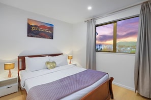 On either side of the bed are matching wood nightstands, each topped with lamps that cast a warm, inviting glow.