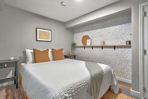 Welcome to our vibrant bedroom adorned with red, white, and gray accents, complete with two convenient side tables and ample, inviting lighting.