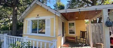 The cute yellow cottage has a wrap around deck!