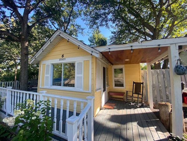 The cute yellow cottage has a wrap around deck!