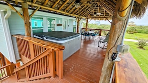 Large covered deck with hot tub and dining area.