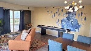 Stylish Living Room and Dining Area featuring Custom Murals, Smart TV, Shuffleboard, Bar Cart and Record Player