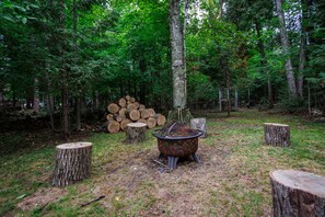 Large wooded yard with fire pit and firewood