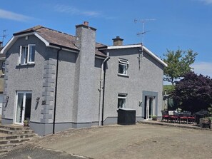 Side view of the property with private parking and patio area (directly beside the kitchen) with seating foe 8-10 guests, gas barbecue (gas provided) and chimenea (logs provided).