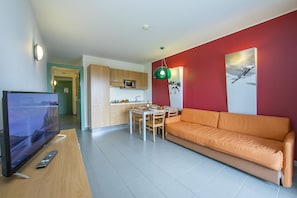 Living area with sofa bed and view of kitchen and corridor