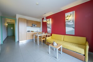 living area with sofa bed and view of kitchen and corridor