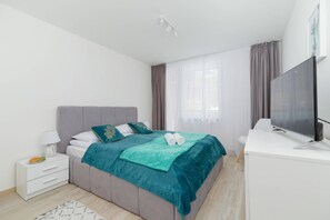 Another cozy bedroom with a double bed, green bedding accents, and minimalist furnishings.
