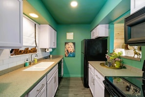 An inviting kitchen featuring trendy green walls contrasted with sleek black appliances, creating a modern and stylish ambiance. 🌿 #KitchenGoals
