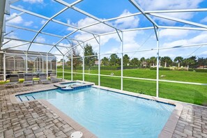 Relax in your private screened-in pool with a hot tub, surrounded by lush greenery and blue skies.