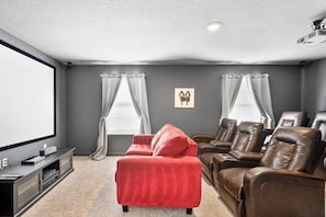 Enjoy movie nights in this cozy home theater with plush seating and a large screen for an immersive experience.
