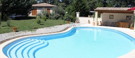 Piscine avec coin bar et au fond le gite Reine des Prés