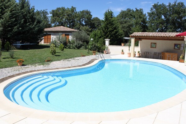 Piscine avec coin bar et au fond le gite Reine des Prés