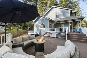 Expansive 2-tiered sundeck with outdoor table, BBQ, fire pit, patio furniture.
