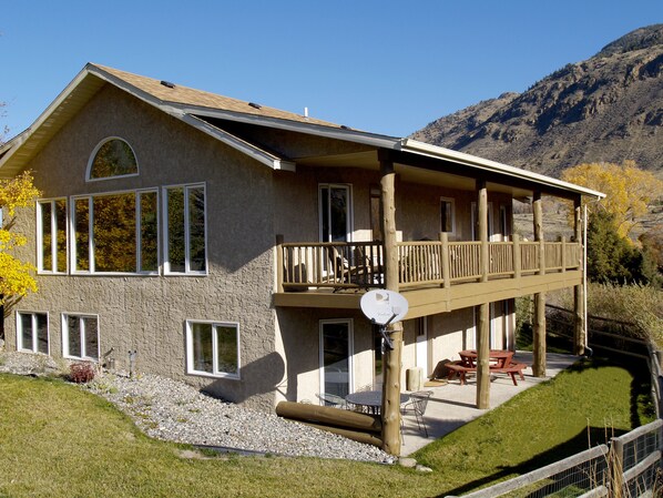 Riverfront home with large deck, patio, yard, and direct river access.