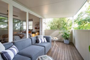 Covered balcony with leafy outlook and water glimpses