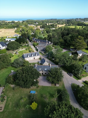 La Moinerie vue du ciel avec la mer au loin et le village de Plévenon à droite.
